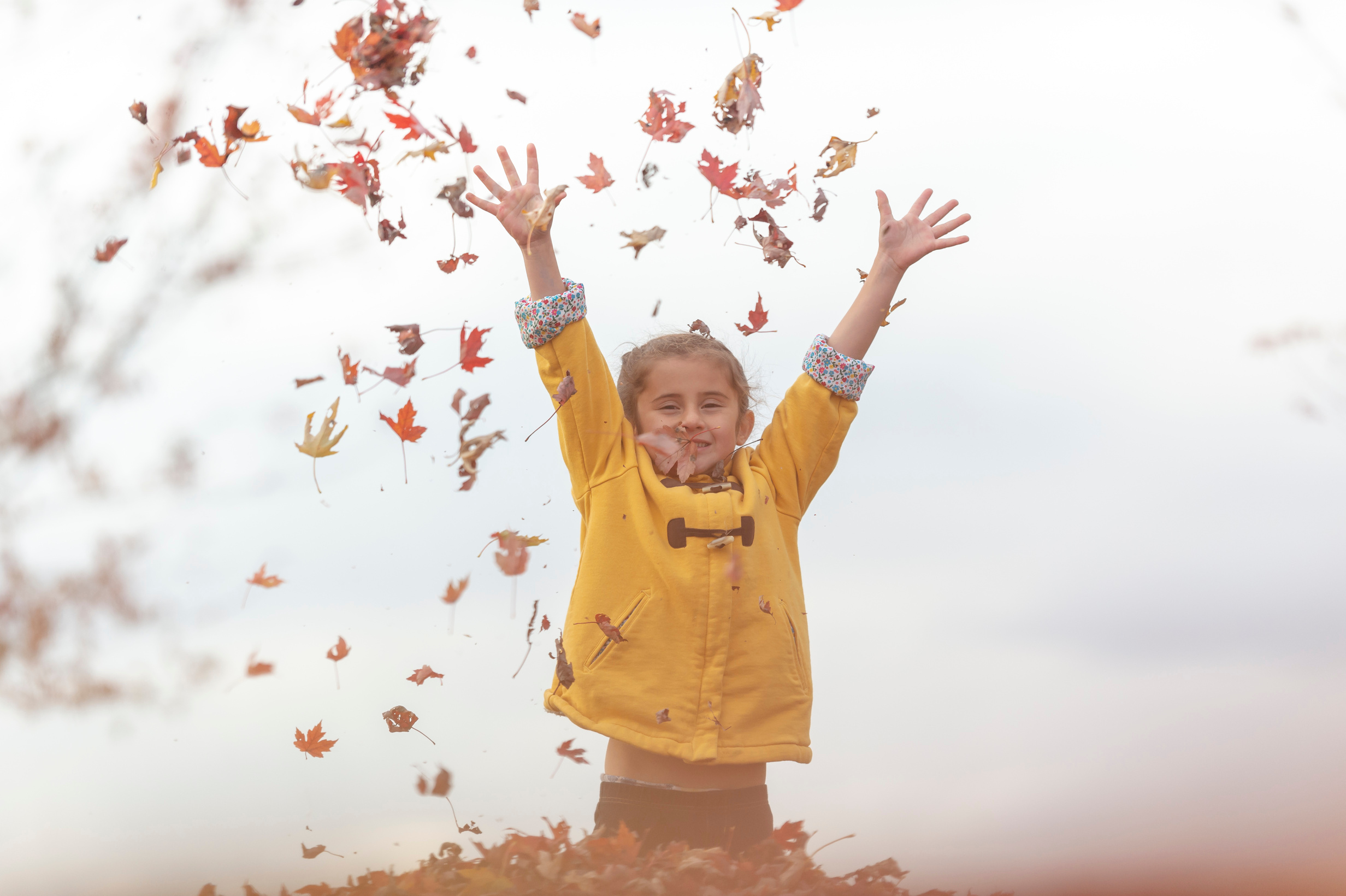 Girl playing in leaf pile